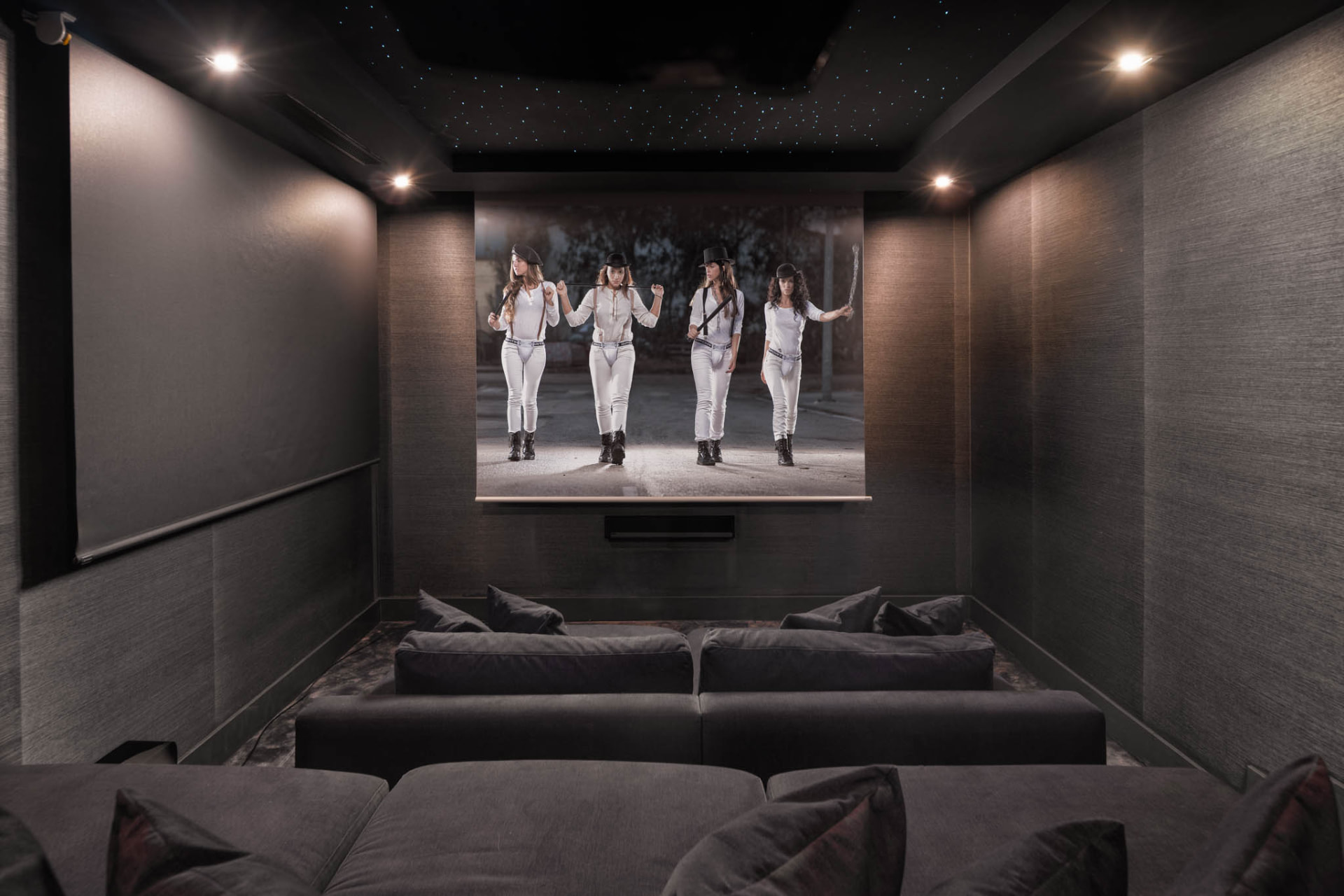 The dedicated cinema room with dark finishes and star-like points of light across the ceiling.